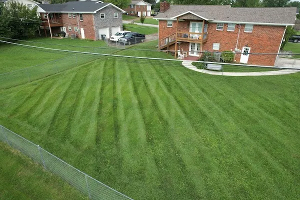 Wide striped front lawn running up to a two-story brick home
